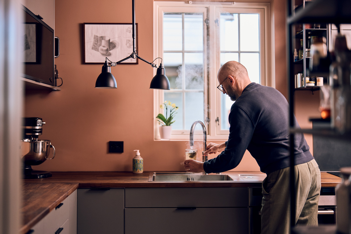 Mann står ved kjøkkenkran og tapper kokende vann.